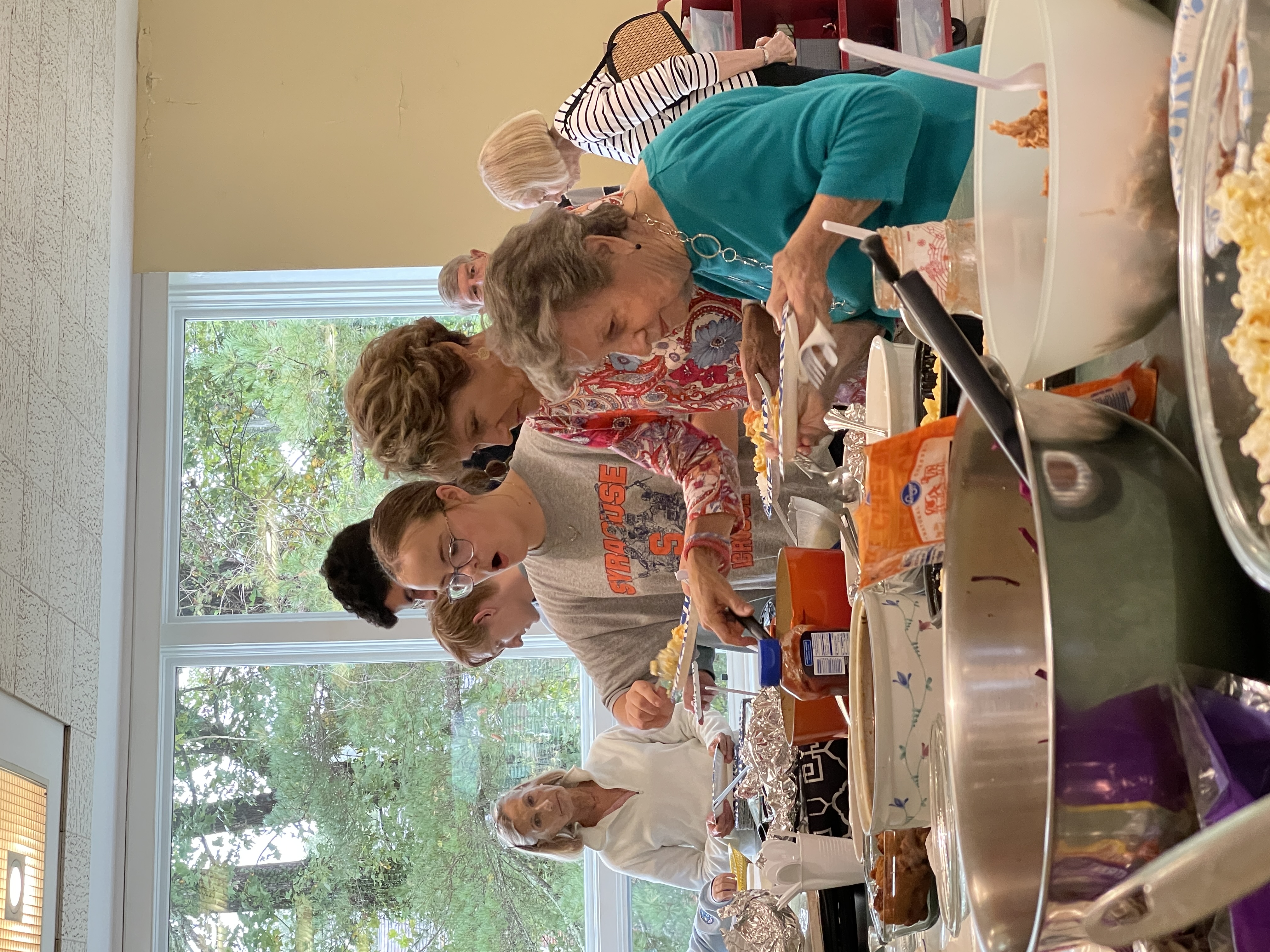 group of adults and college students gathered at a table to eat